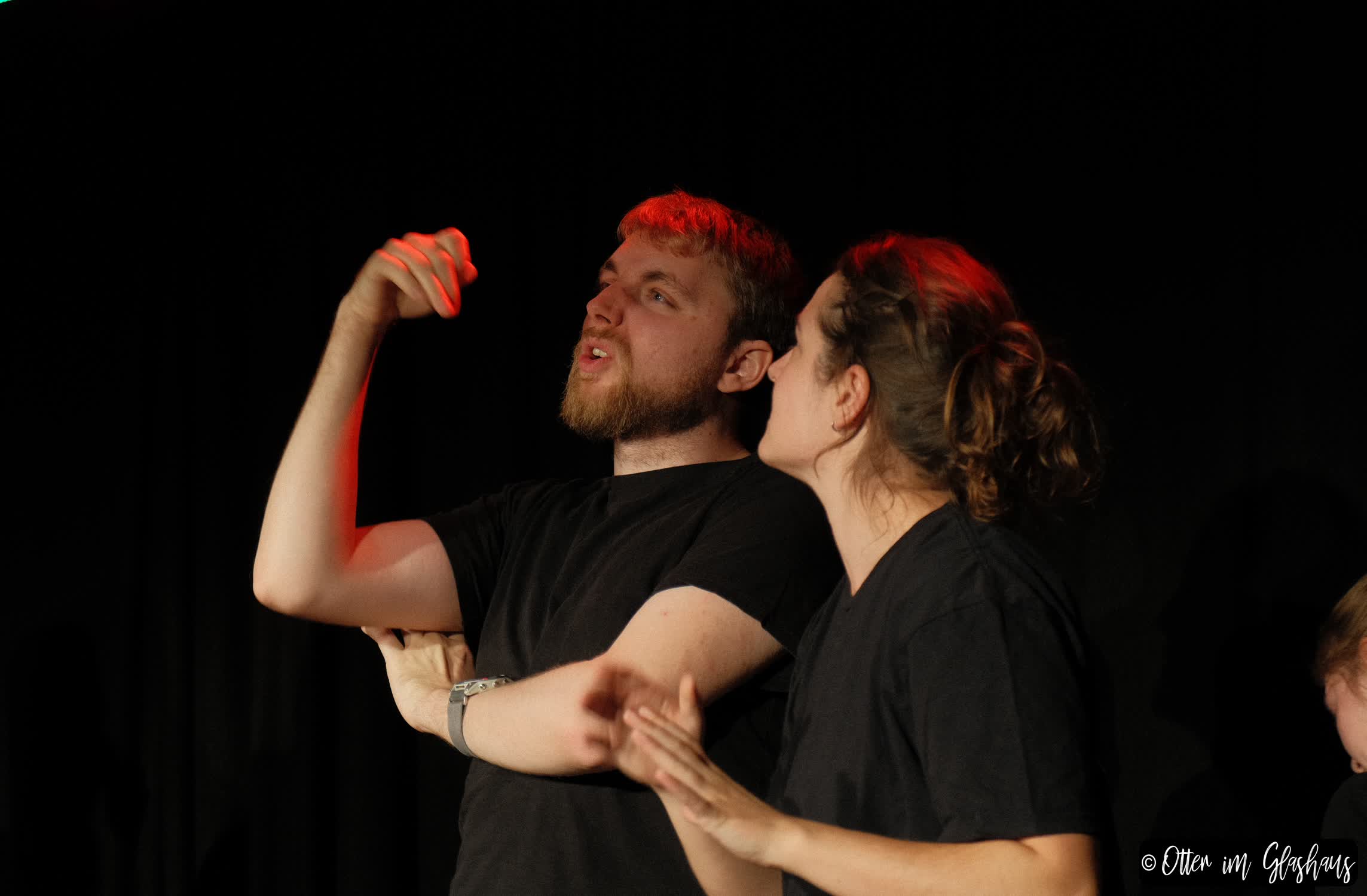 Zwei Schauspielende. Der eine hat seine Arme verschränkt und schaut aus, als ob er sich beschwert.